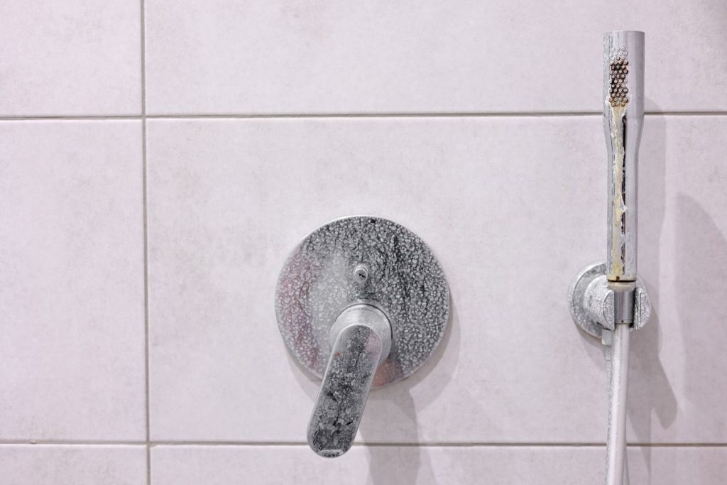 Dirty calcified shower mixer tap, faucet with limescale on it, plaque from hard water